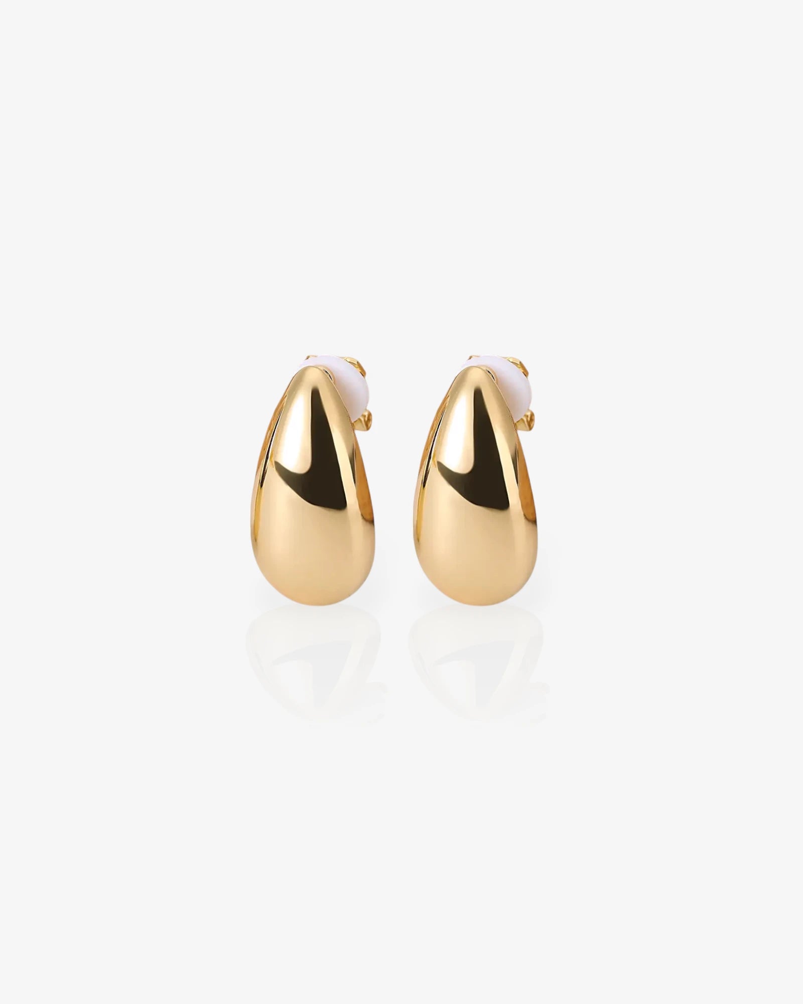 Gold earrings on a light gray background