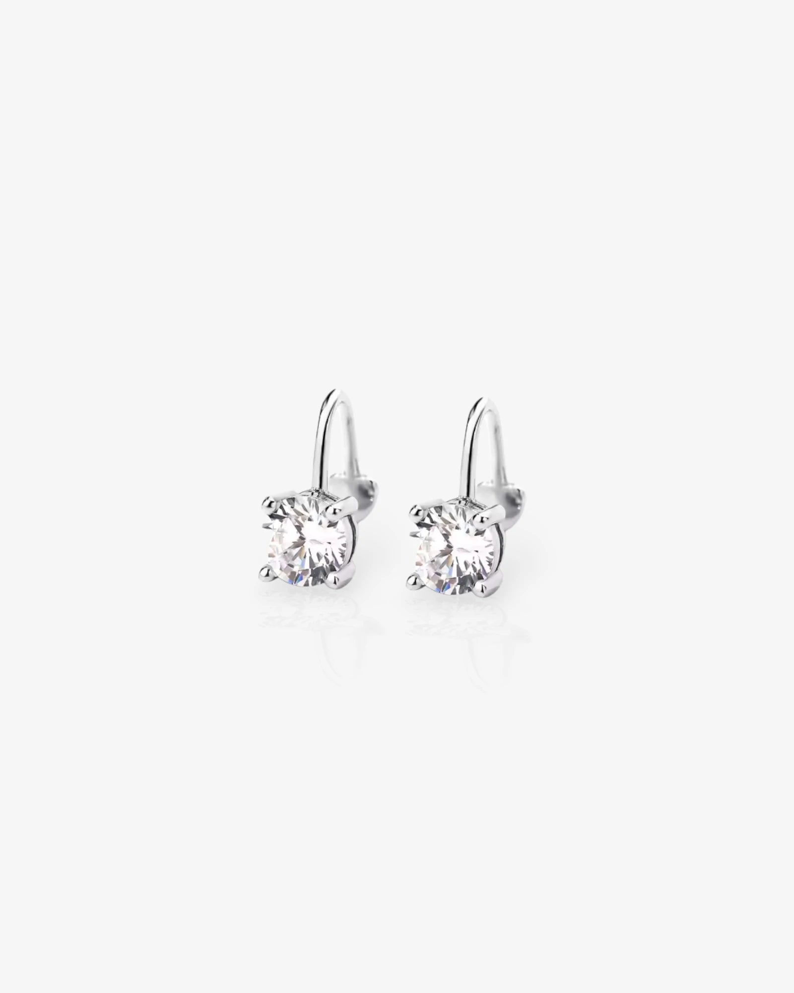 Pair of silver earrings with clear gemstones on a white background