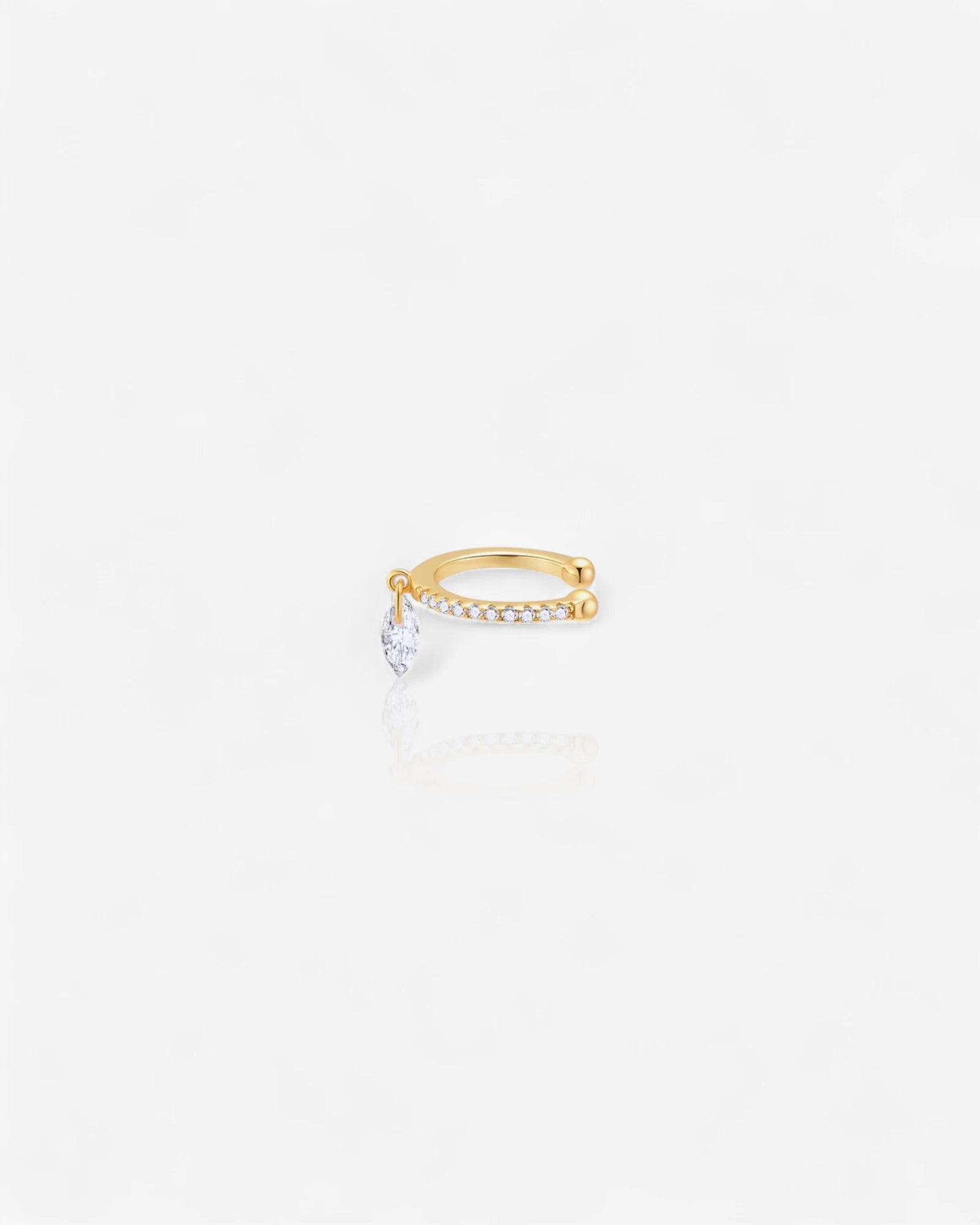 Gold ear cuff with a small diamond on a white background